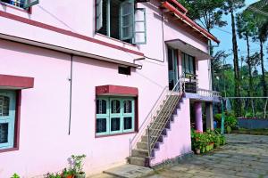 a pink house with stairs on the side of it at Giri Darshini Homestay - 3BH, Simple Rooms with Pool & Private Falls in Chikmagalūr