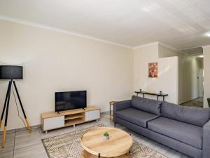 a living room with a couch and a tv at Olive House in Brackenfell