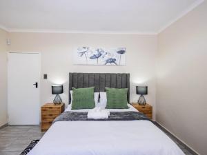 a bedroom with a large bed with green pillows at Olive House in Brackenfell