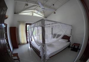 a bedroom with a bed with a mosquito net at Shade Villa in Galle