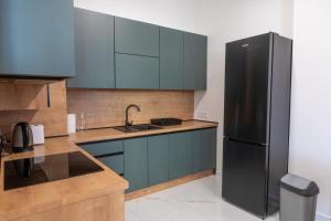 a kitchen with blue cabinets and a black refrigerator at Top Apartmán v Central Point Humenné M in Humenné