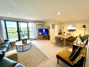 a living room with a couch and a table and a television at Gosfords Best Location with Views in Gosford