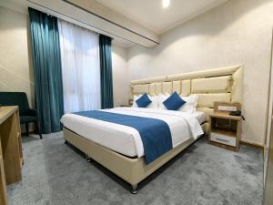 a bedroom with a large bed with blue and white pillows at Chilonzor Hotel in Tashkent