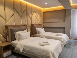 two beds in a hotel room with white sheets at Chilonzor Hotel in Tashkent