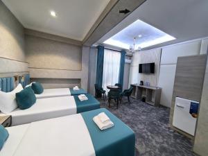a hotel room with two beds and a desk at Chilonzor Hotel in Tashkent