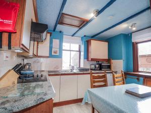 a kitchen with blue walls and a table with chairs at Islay Cottage in Kincraig