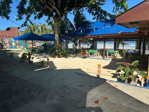 a patio with tables and umbrellas on the beach at Little Miami Beach Resort in Anda