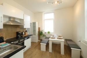 a white kitchen with a table and a sink at Studio Apartment nahe Lüneburg in Bienenbüttel +6 photos