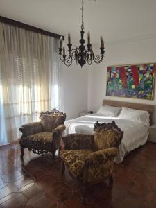 a bedroom with a bed and two chairs and a chandelier at Villa Cantalupo 1 in Sillavengo