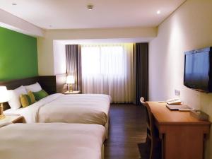 ein Hotelzimmer mit zwei Betten und einem Flachbildfernseher in der Unterkunft Green World Triple Beds in Taipeh