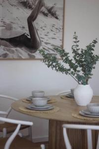 a table with plates and a vase with a plant on it at Saltwater at Warilla Beach in Lake Illawarra