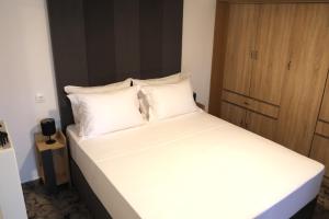 a bed with white sheets and pillows in a room at X N Skiathos in Skiathos