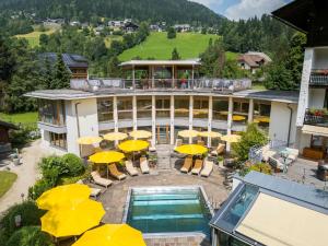 a hotel with yellow umbrellas and a swimming pool at Naturhotel Ortners Eschenhof in Bad Kleinkirchheim