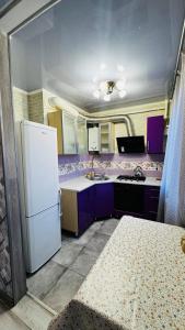 a kitchen with purple cabinets and a white refrigerator at Vinnytsia, Vyshenka in Vinnytsya