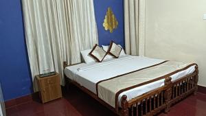 a bedroom with a bed with a blue wall at Mermaid Manor in Varkala