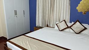 a bedroom with a bed with two pillows on it at Mermaid Manor in Varkala