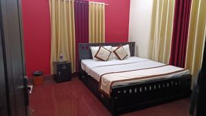 a bedroom with a bed with red walls at Mermaid Manor in Varkala