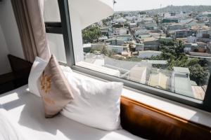 a bed with pillows sitting in front of a window at Khách Sạn Hạo Nhiên in Buon Ma Thuot