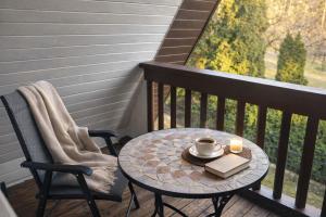 a table with a cup of coffee and a candle on a balcony at Pamiškės Villa in Kulautuva