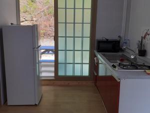 a kitchen with a white refrigerator and a stove at Geoje Milky Way Pension in Geoje