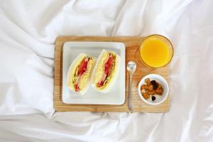 a plate with a sandwich and a cup of orange juice at Seogwipo Jan-Jan Pension in Seogwipo