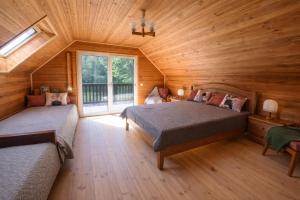 a bedroom with two beds in a wooden cabin at Pamiškės Villa in Kulautuva