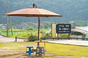 a table and chairs under an umbrella next to a road at Yangpyeong Newspace in Yangpyeong