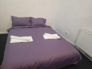 a purple bed with two white towels on it at Eroilor Downtown Studio in Cluj-Napoca