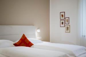 two white beds in a bedroom with a red pillow at Villa Sabine in Merano