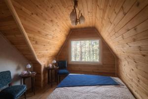 a bedroom in a log cabin with a bed and two chairs at Pamiškės Villa in Kulautuva
