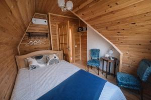 a bedroom in a log cabin with a bed and two chairs at Pamiškės Villa in Kulautuva +8 photos