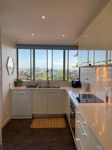 a kitchen with white cabinets and a large window at Gosfords Best Location with Views in Gosford