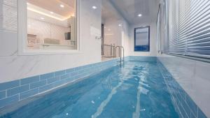 a swimming pool in a bathroom with a blue tiled floor at Gapyeong Zav Pool Villa in Gapyeong