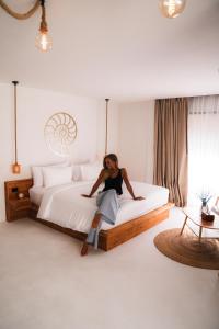 a woman sitting on a bed in a room at Samaraya Wellness Resort - Adults Only in Lipa Noi