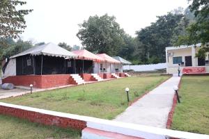 a group of tents in a field with a sidewalk at Maa Mandakini Resort & Hotel in Chitrakoot