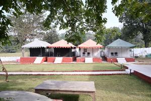 a group of tents with tables in a field at Maa Mandakini Resort & Hotel in Chitrakoot