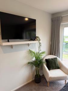 a living room with a chair and a tv on a wall at Riverside Retreat with River views in Auckland