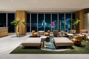 a lobby with tables and chairs and a view of the city at Hilton Garden Inn Yokohama Minatomirai in Yokohama