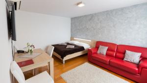 a living room with a red couch and a bed at Dream Hotel in Velika Gorica