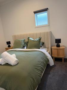 a bedroom with a large bed with green sheets and pillows at The Nook in Greytown