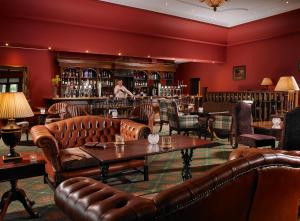 a bar with leather couches and a man behind the bar at Hotel Woodstock Ennis in Ennis