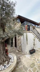 a stone building with a balcony and a tree at SİSU ALAÇATI OTEL in Çeşme