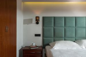 a bedroom with a green headboard and a wooden cabinet at Athens Odeon Hotel in Athens