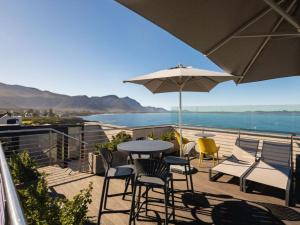 a patio with a table and chairs and an umbrella at Hermanus Waterfront Boho Studio Apartment, Whale Coast Hideaway in Hermanus