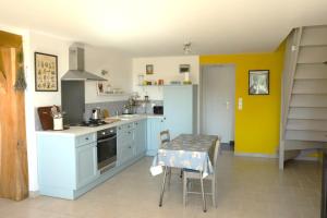 a kitchen with a table and a kitchen with yellow walls at Maison Mayjune Cottage in Irai