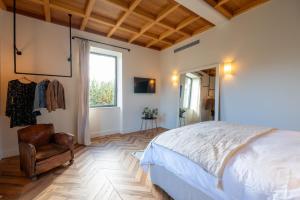 a bedroom with a bed and a chair and a window at La Maison et l'Orangerie in Saint-Jean-des-Vignes