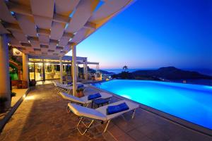 a swimming pool with lounge chairs next to a building at Stefanos Village Hotel in Plakias