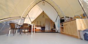 a tent with a table and chairs and a bedroom at The Hill Glamping in Yeoju