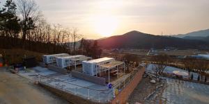 a building under construction with the sunset in the background at The Hill Glamping in Yeoju +35 photos