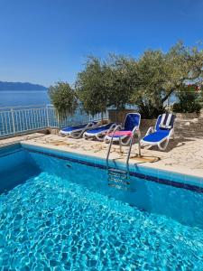 a swimming pool with chairs and a row of water at Villa Falcon in Podaca
